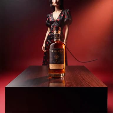 VELMORE amber bottle placed on the black table with matching red light and a surface reflection