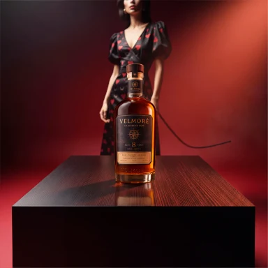VELMORE amber bottle placed on the black table with matching red light and a surface reflection